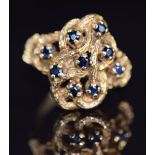 A 9ct gold ring set with sapphires in a textured knot setting, 5.2g, size N