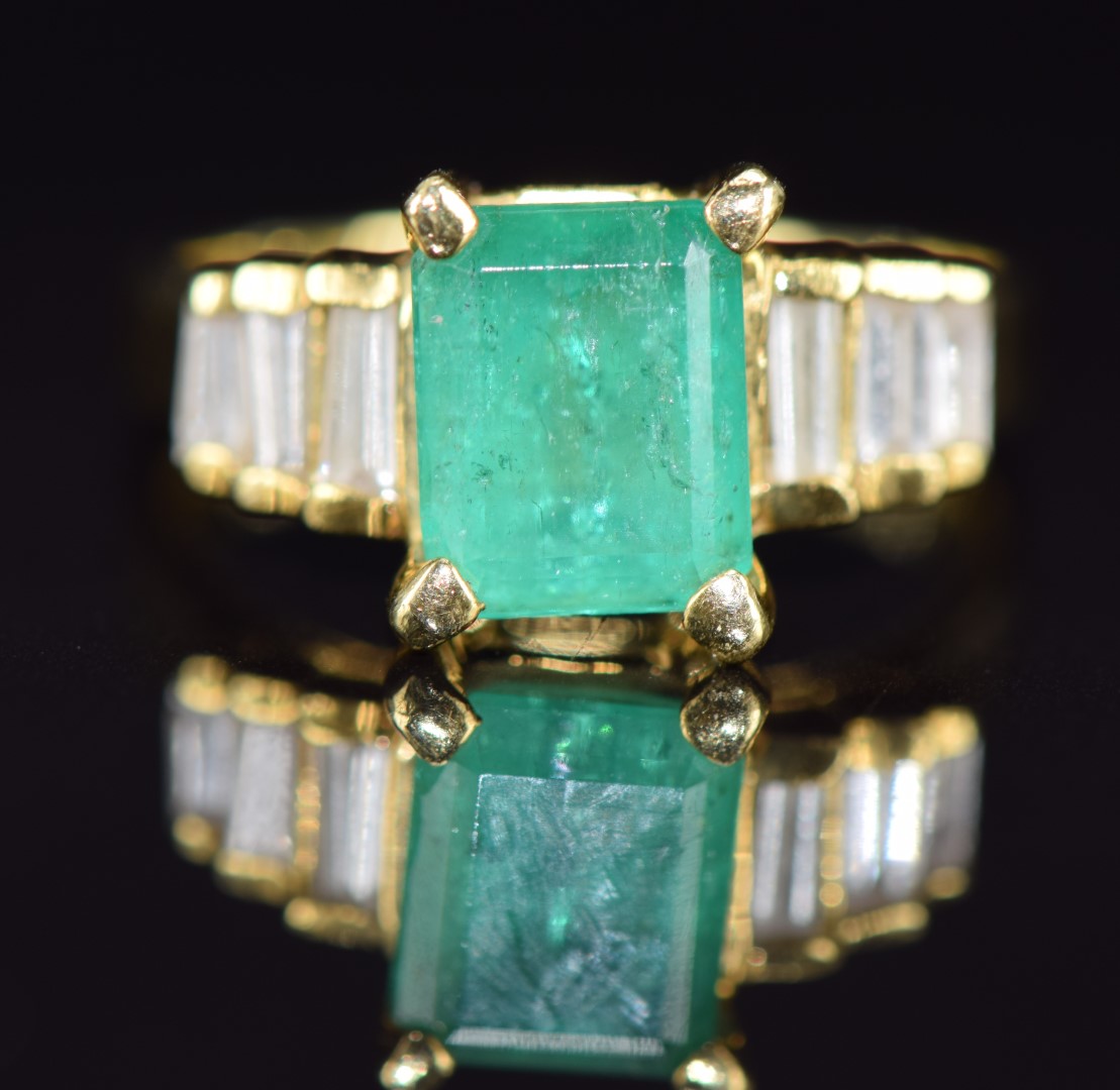 An 18k gold ring set with an emerald cut emerald of approximately 1.9ct and six baguette cut