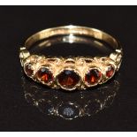 A 9ct gold ring set with five round cut garnets, 2.4g, size O