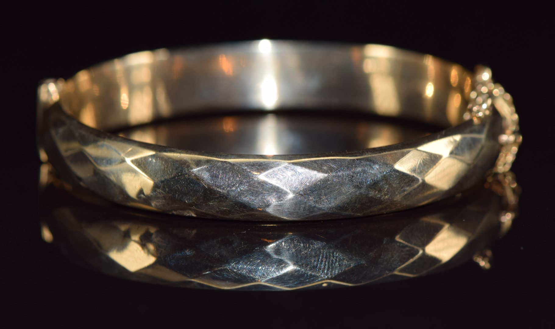 A 9ct gold bangle with faceted design, 13g