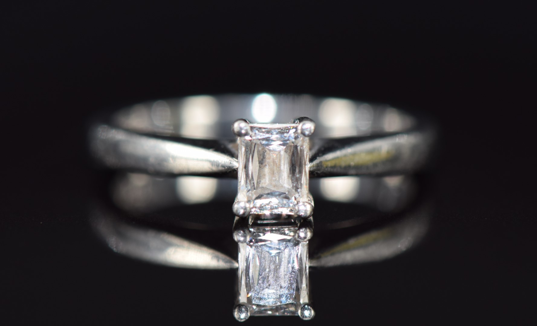 A platinum ring set with an 0.4ct emerald cut diamond, with paperwork from Beaverbrooks, 3.9g,