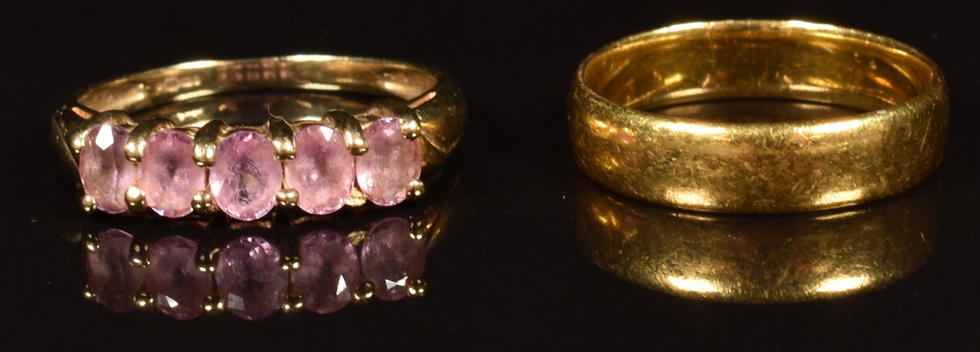 A 9ct gold ring set with five oval cut pink sapphires (2.1g) and a 22ct gold wedding band (3.5g)