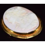 A yellow metal brooch set with a coral cameo depicting a young woman, 24.8g