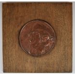 Arts & Crafts copper plaque depicting an angel holding a putti, diameter 16cm, on oak panel, width