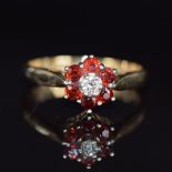 A 9ct gold ring set with a diamond surrounded by garnets, 2.3g, size K