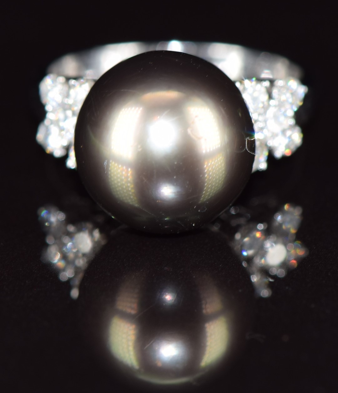An 18ct white gold ring set with a 14ct black South Sea pearl, and with five diamonds to each