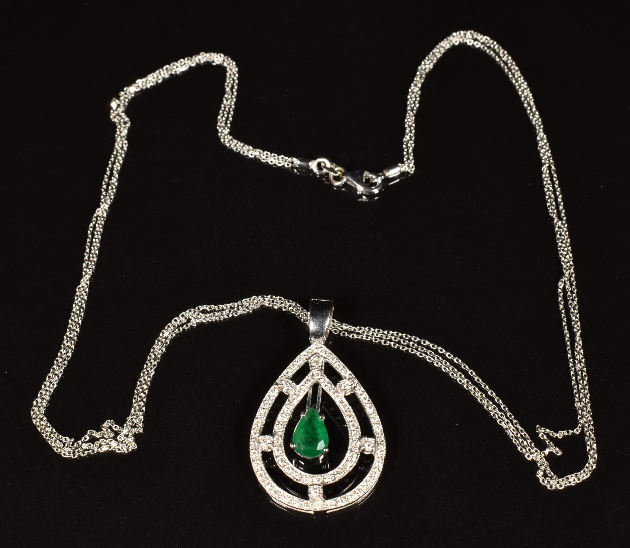 A 18k white gold pendant set with a pear cut emerald of approximately 0.8ct surrounded by