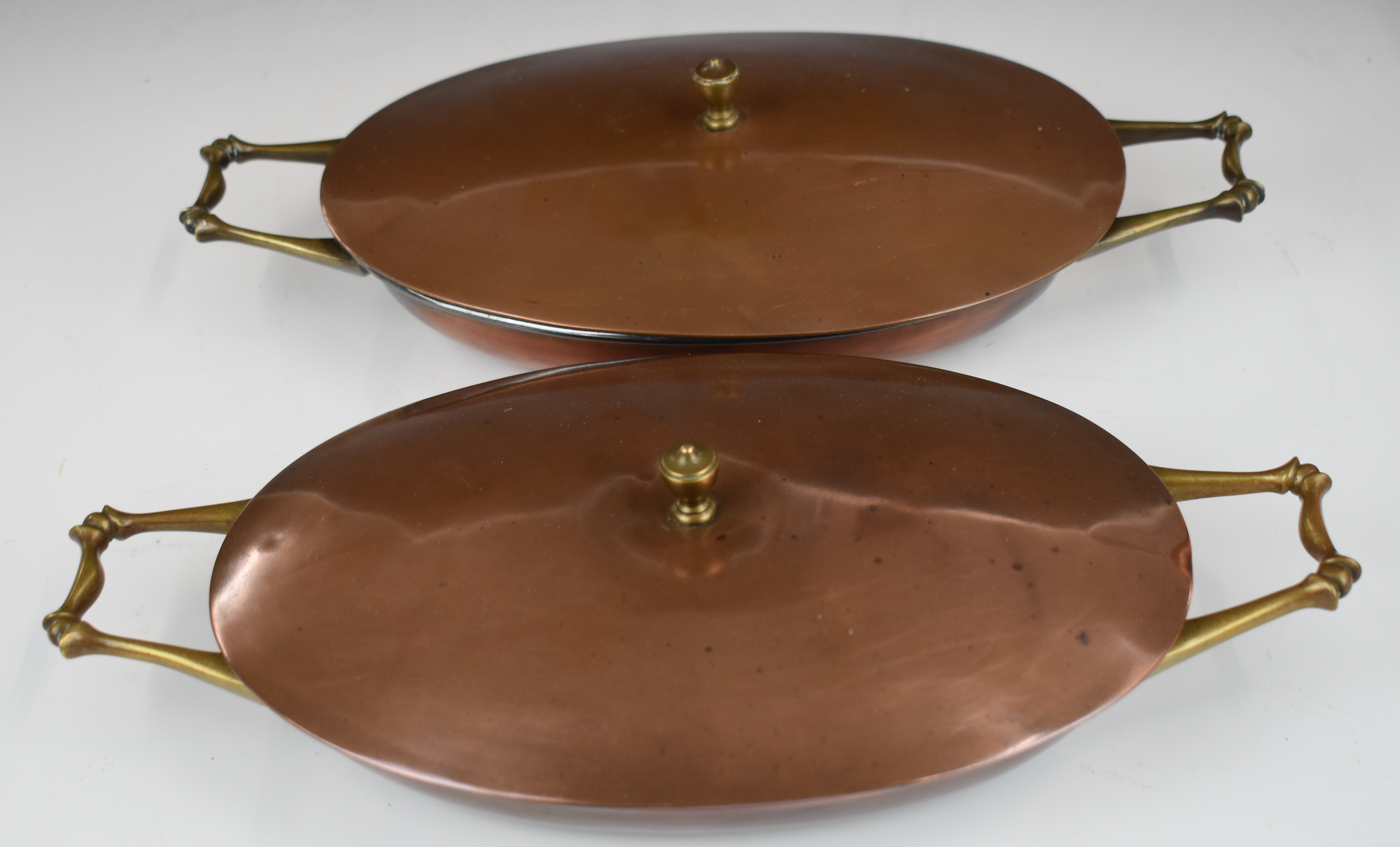 WAS Benson Arts & Crafts pair of twin handled copper and brass covered dishes, length 32cm