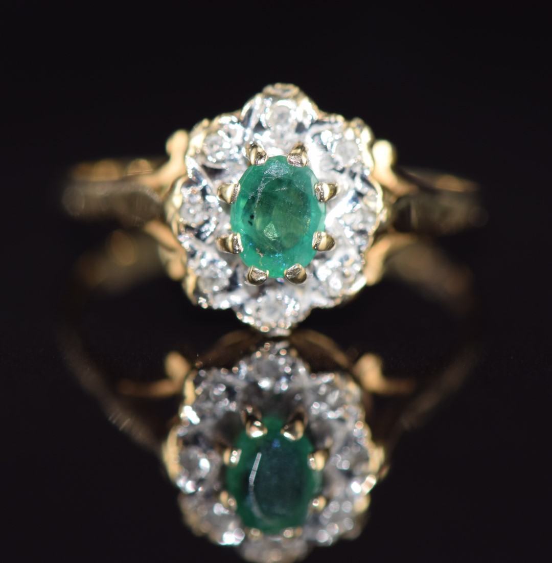 A 9ct gold ring set with an oval cut emerald surrounded by diamonds, 2g, size O