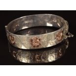 A hallmarked silver bangle with gold floral decoration