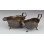 Two early 20thC hallmarked silver sauce boats, both with shaped edges and raised on three feet,