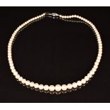 A single strand of cultured pearls with an 18ct white gold clasp set with an emerald and diamonds
