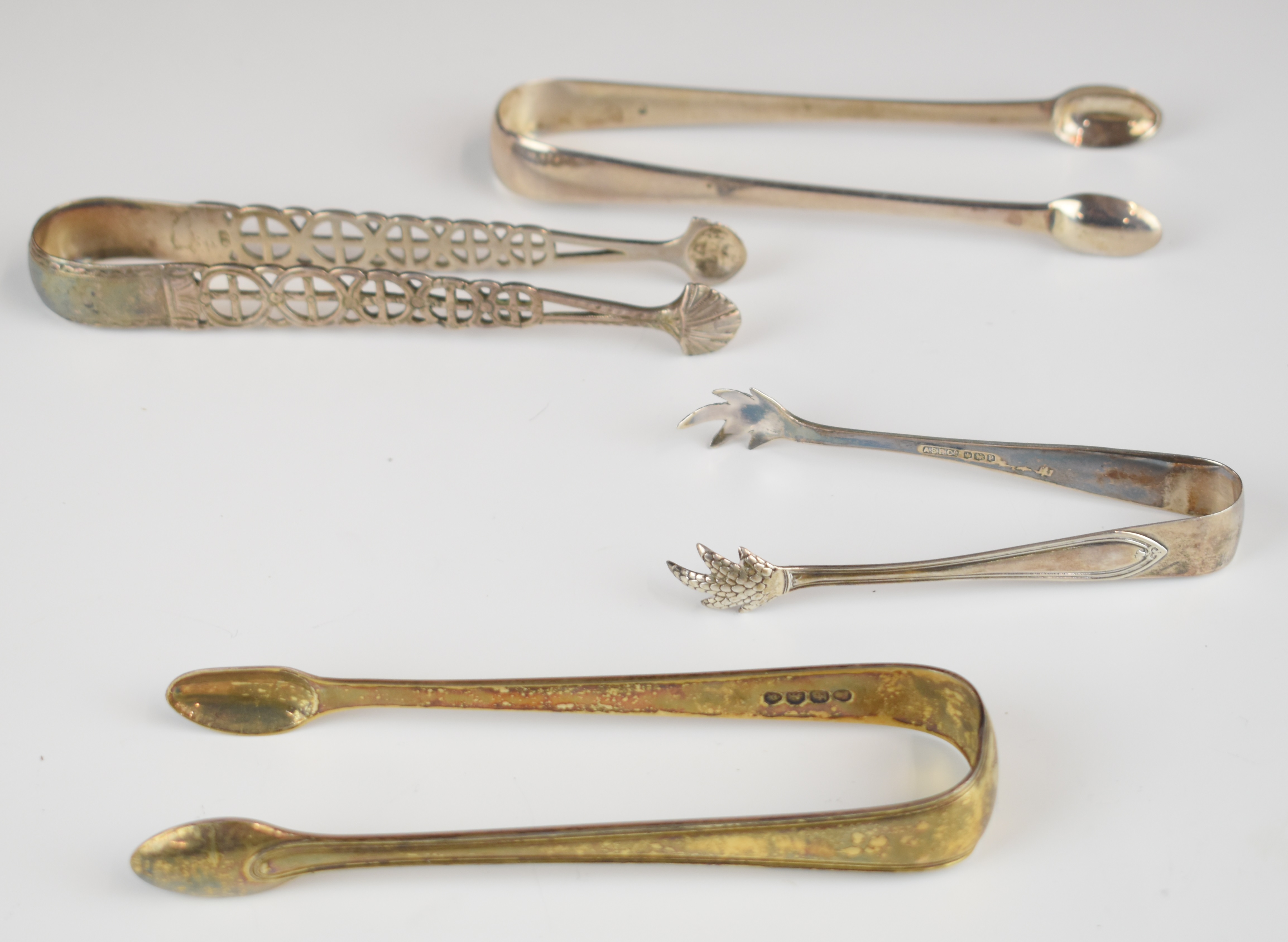 Four sets of hallmarked silver sugar tongs to include a silver gilt pair, London 1821, maker's