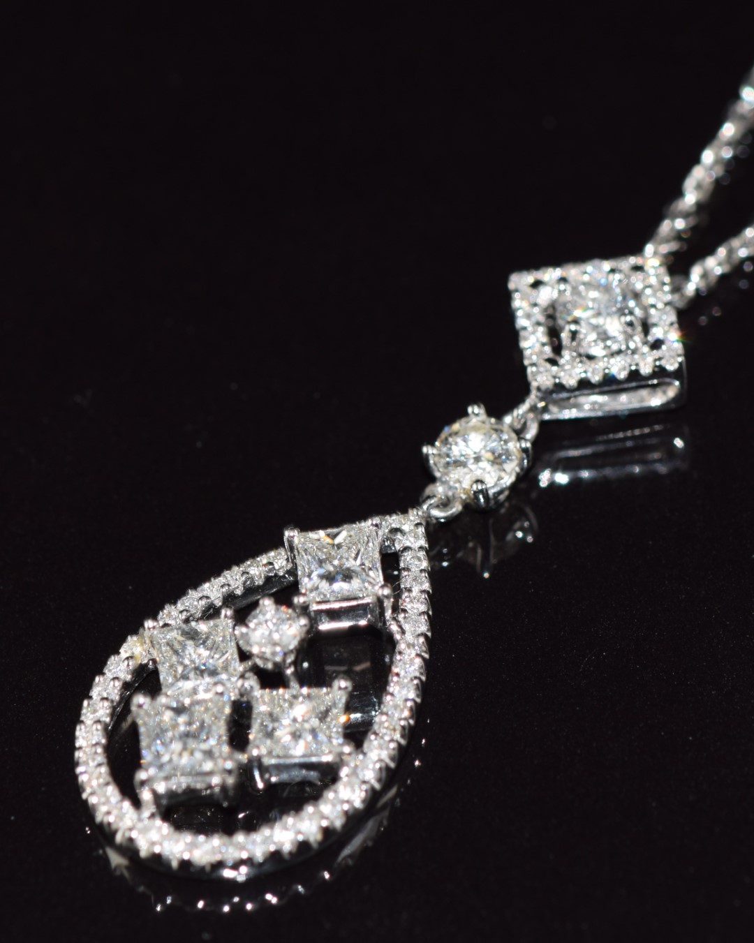 An 18ct white gold pendant set with four princess cut diamonds and further round brilliant cut