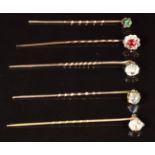 Four 9ct gold stick pins, one set with an emerald, one moonstone, one spinel and one paste