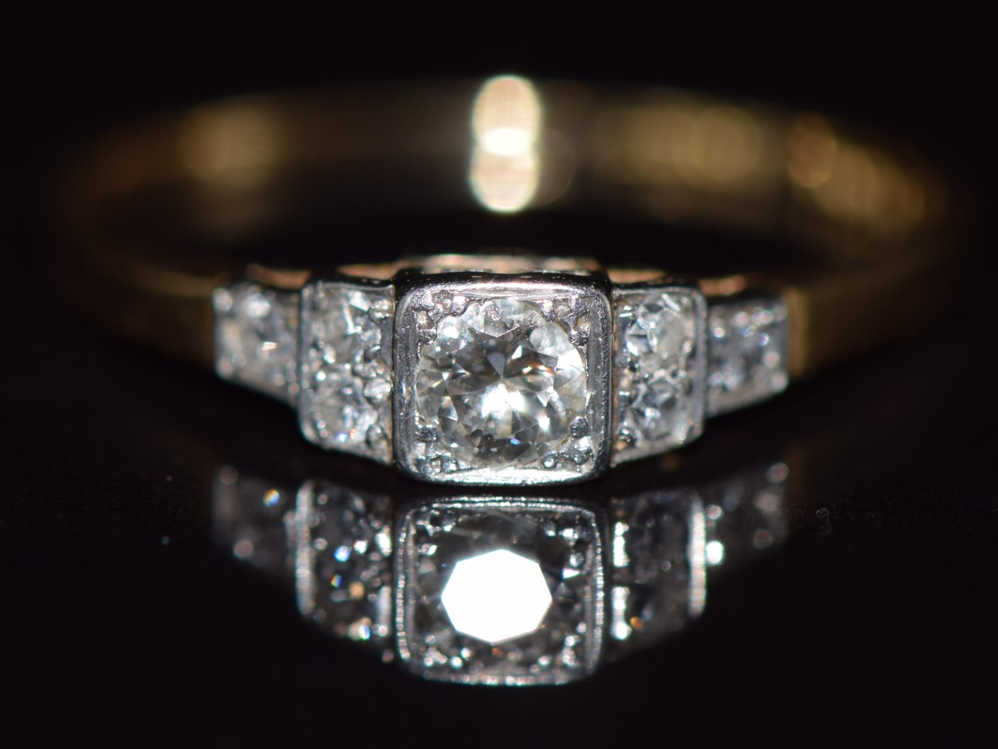 Art Deco 18ct gold ring set with seven diamonds in a tiered platinum setting, the largest diamond