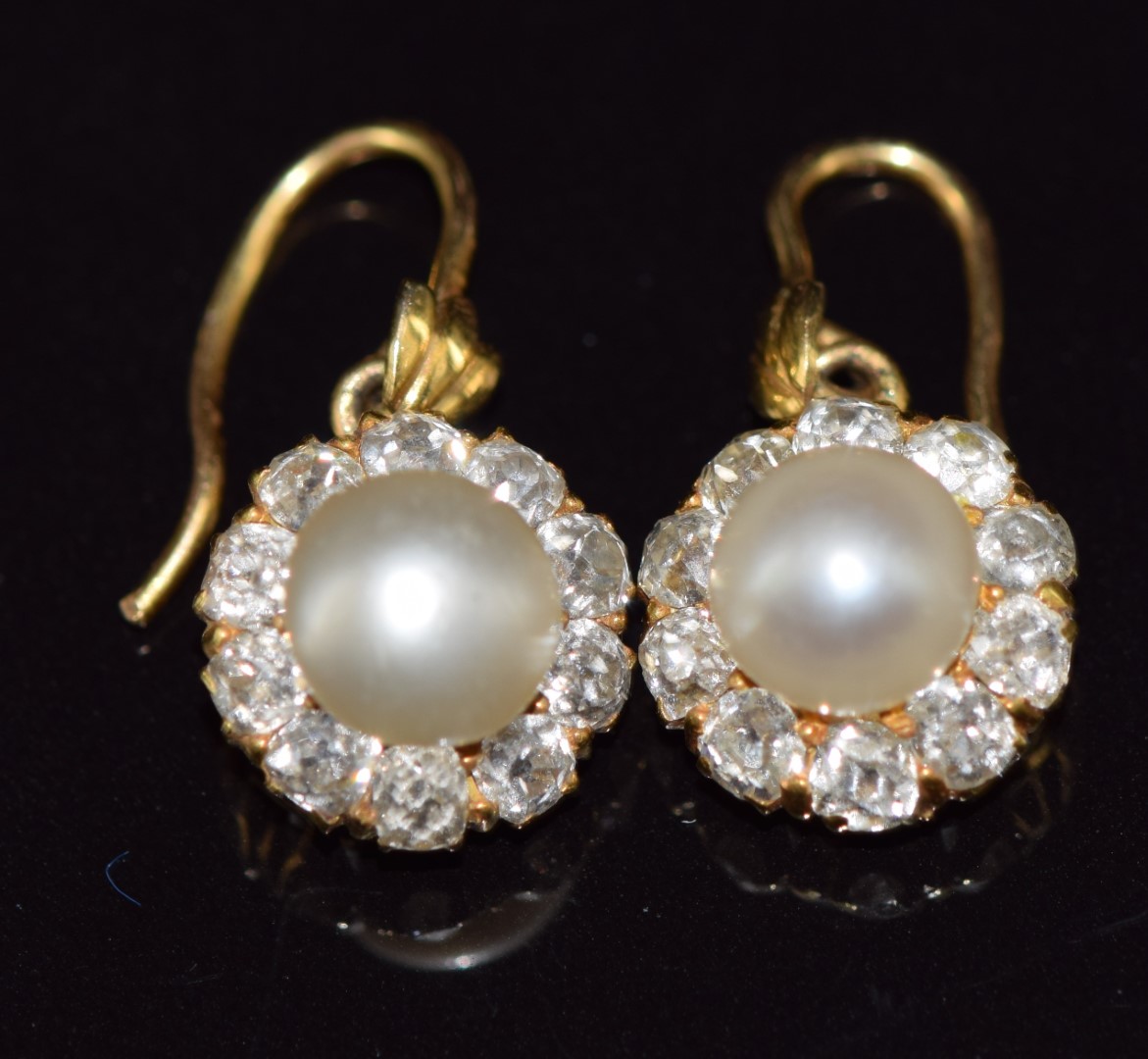 A pair of c1900 18ct gold earrings, each set with a natural pearl measuring 6.4mm surrounded by