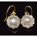 A pair of c1900 18ct gold earrings, each set with a natural pearl measuring 6.4mm surrounded by
