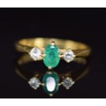 An 18ct gold ring set with an oval cut emerald of approximately 0.5ct and two diamonds, 3g, size L