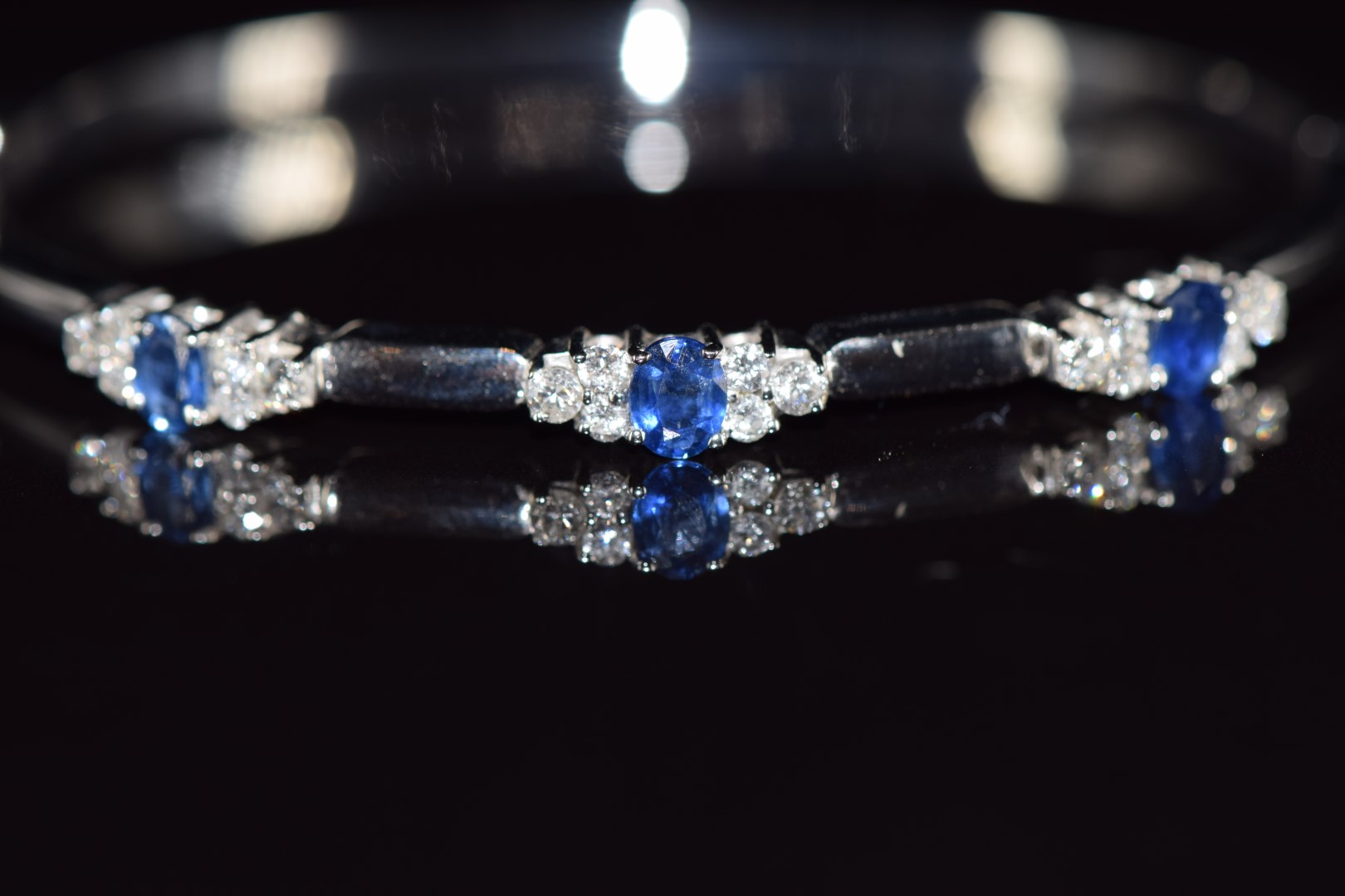 An 18ct white gold bangle set with three oval cut sapphires, each approximately 0.3ct and eighteen - Image 2 of 3