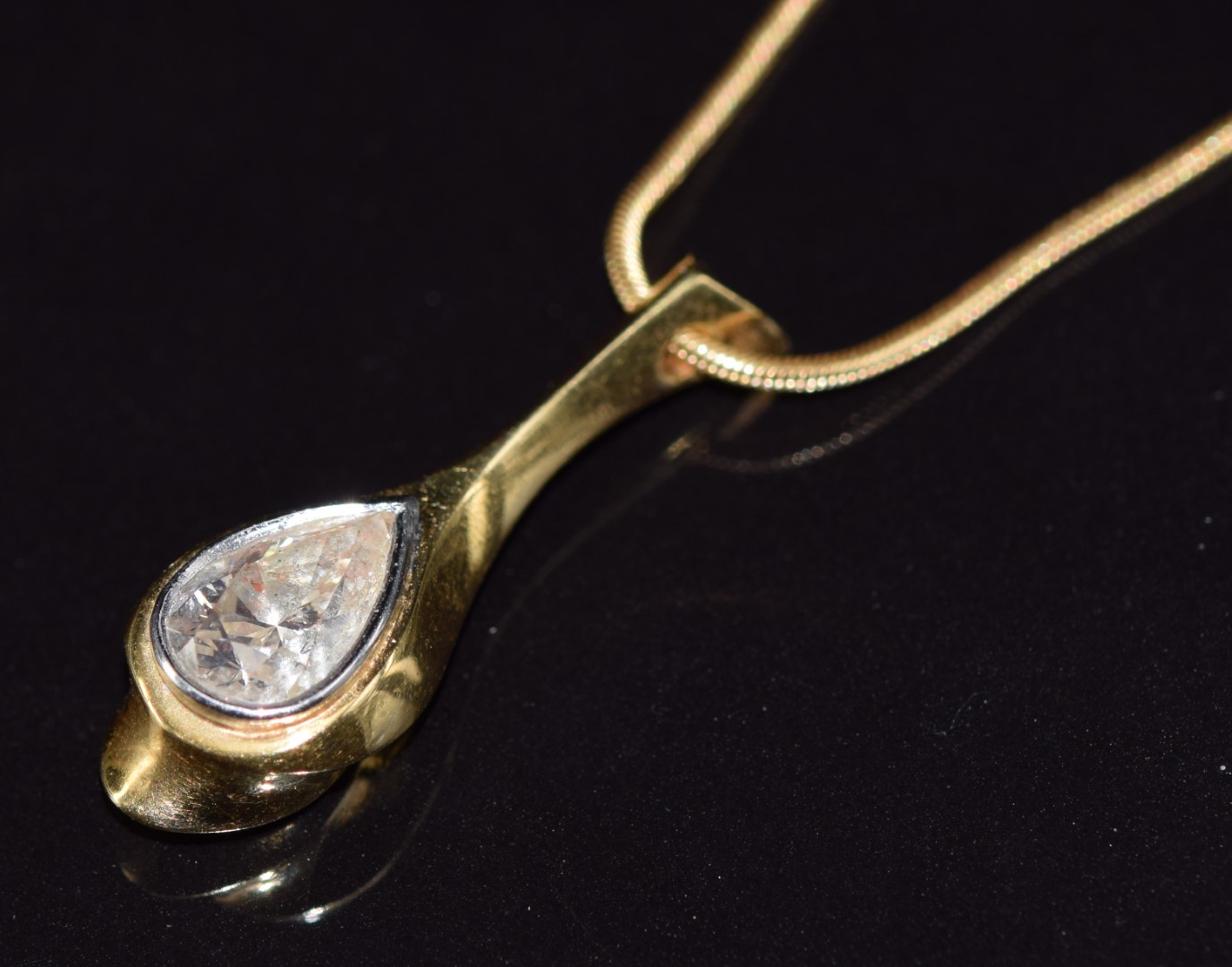 An 18ct gold bespoke pendant set with a 1.5ct pear cut diamond, on an 18ct gold chain, 9.1g