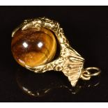 A 9ct gold charm in the form of a claw set with tiger's eye, 5.5g
