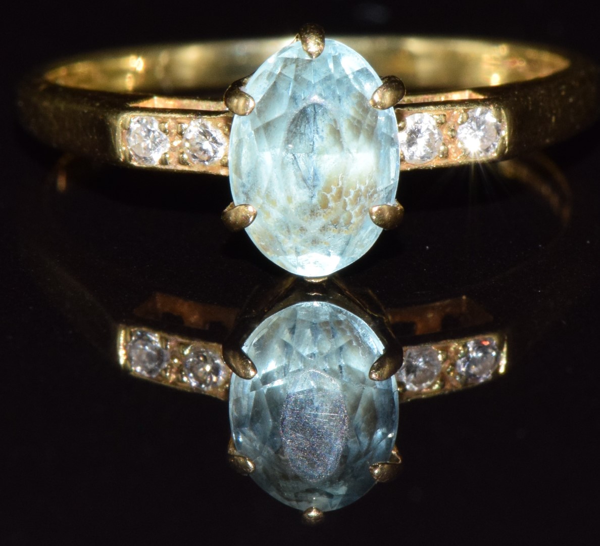 An 18ct gold ring set with an oval cut aquamarine and diamonds, 2.3g, size J