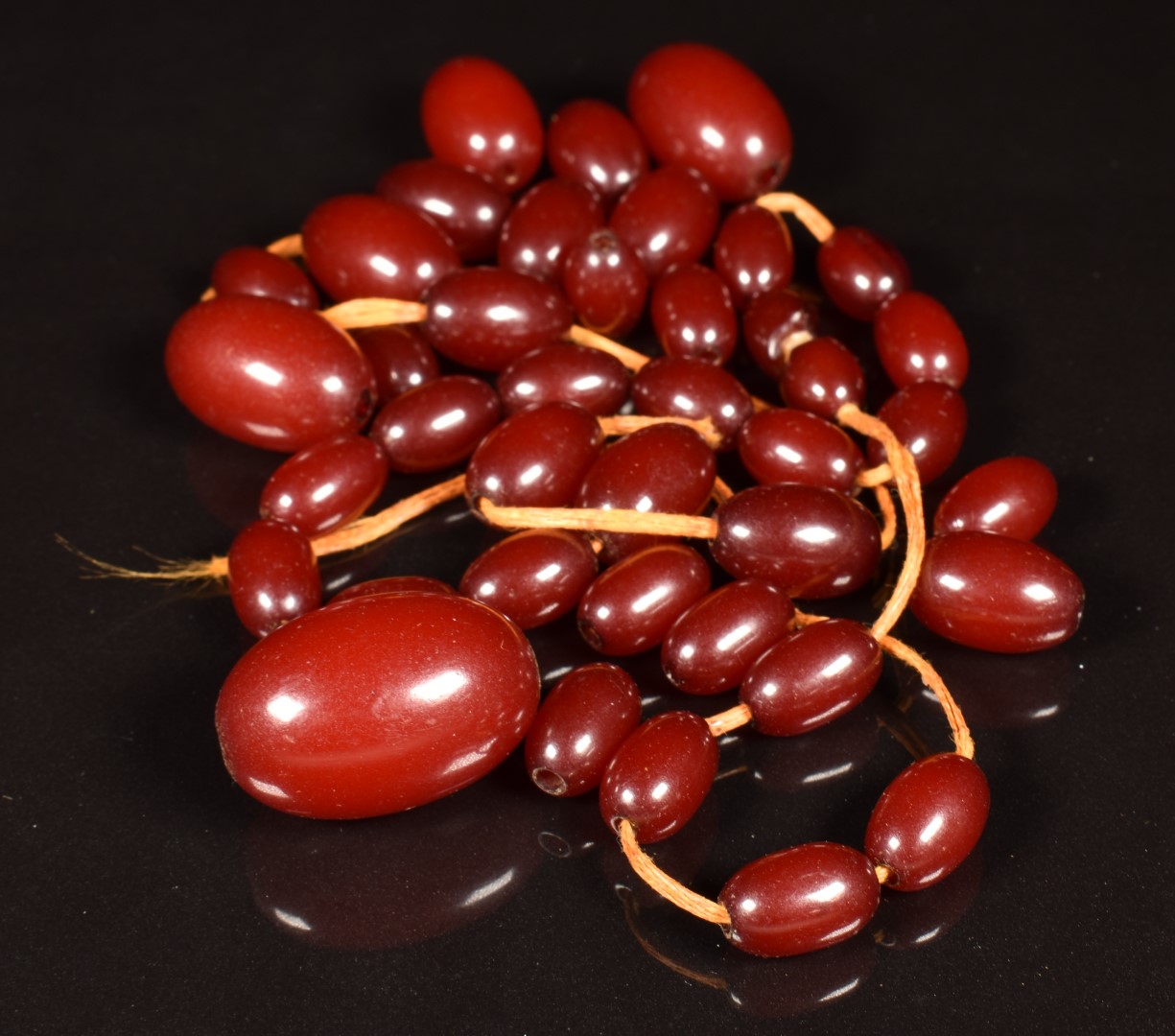 A cherry amber necklace, the largest bead 16 x 25mm. 33.7g