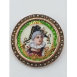 (NB) A late 19th century Limoges coloured enamel circular brooch, decorated Columbine wearing a