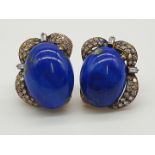 (NB) A pair of yellow metal ear clips, set oval cabochon lapis lazuli with pave diamond mounts,
