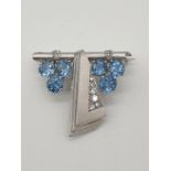 (NB) A white metal brooch set blue zircons and diamonds, stamped 18ct, by Alabaster & Wilson, (no