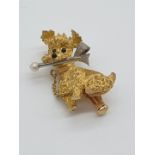 (NB) A yellow metal brooch of a seated poodle holding pin in mouth, stamped 750, by Alabaster and
