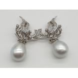 (NB) A pair of diamond set ear clips, decorated with stylized ribbons and entwined horse shoe,