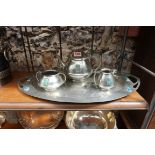 An Arts & Crafts pewter three piece tea set and tray, by William Hutton & Sons, applied with