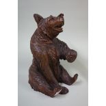 A good and large Black Forest carved wood seated bear, hinged at the shoulders and with inset