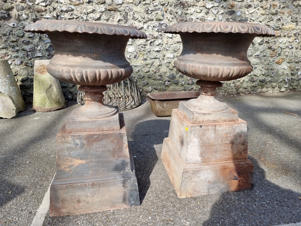 A pair of cast iron urns and pedestals, 80cm high.