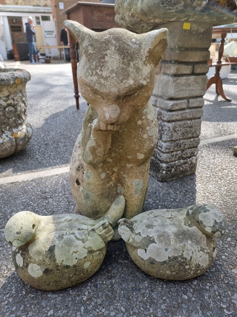 A composition stone seated cat; together with a small pair of composition stone birds.