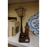 An early 20th century novelty carved wood figural table lamp, representing a Dickens style figure,