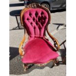 A Victorian walnut and button upholstered open armchair.