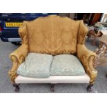 An antique wing back two seater settee, on claw and ball feet to the front. Provenance: The Nash