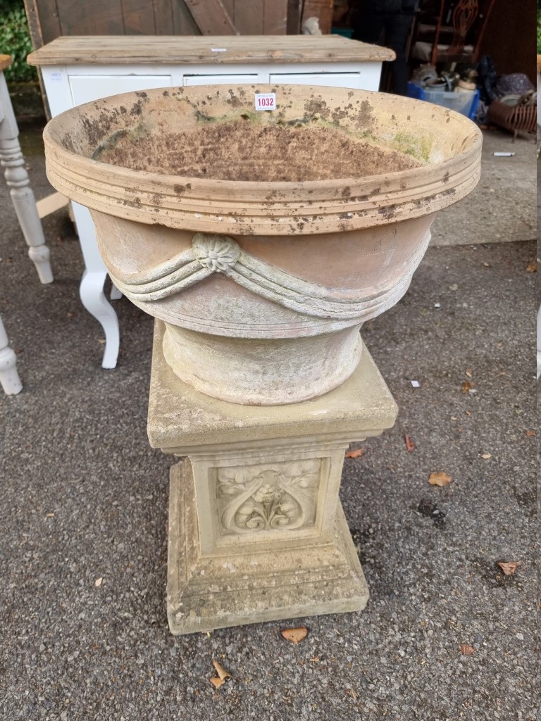 A terracotta urn on associated pedestal.