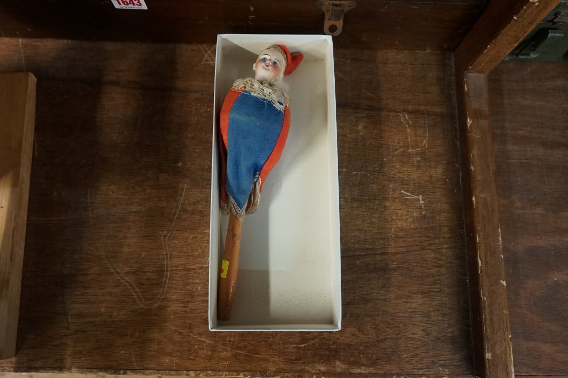 An early 20th century bisque head musical rattle doll, in blue and red jester costume, head