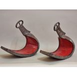 Two similar Japanese steel stirrups, probably late Edo, each with stylized decoration.