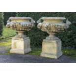 A pair of composition stone urns on pedestals