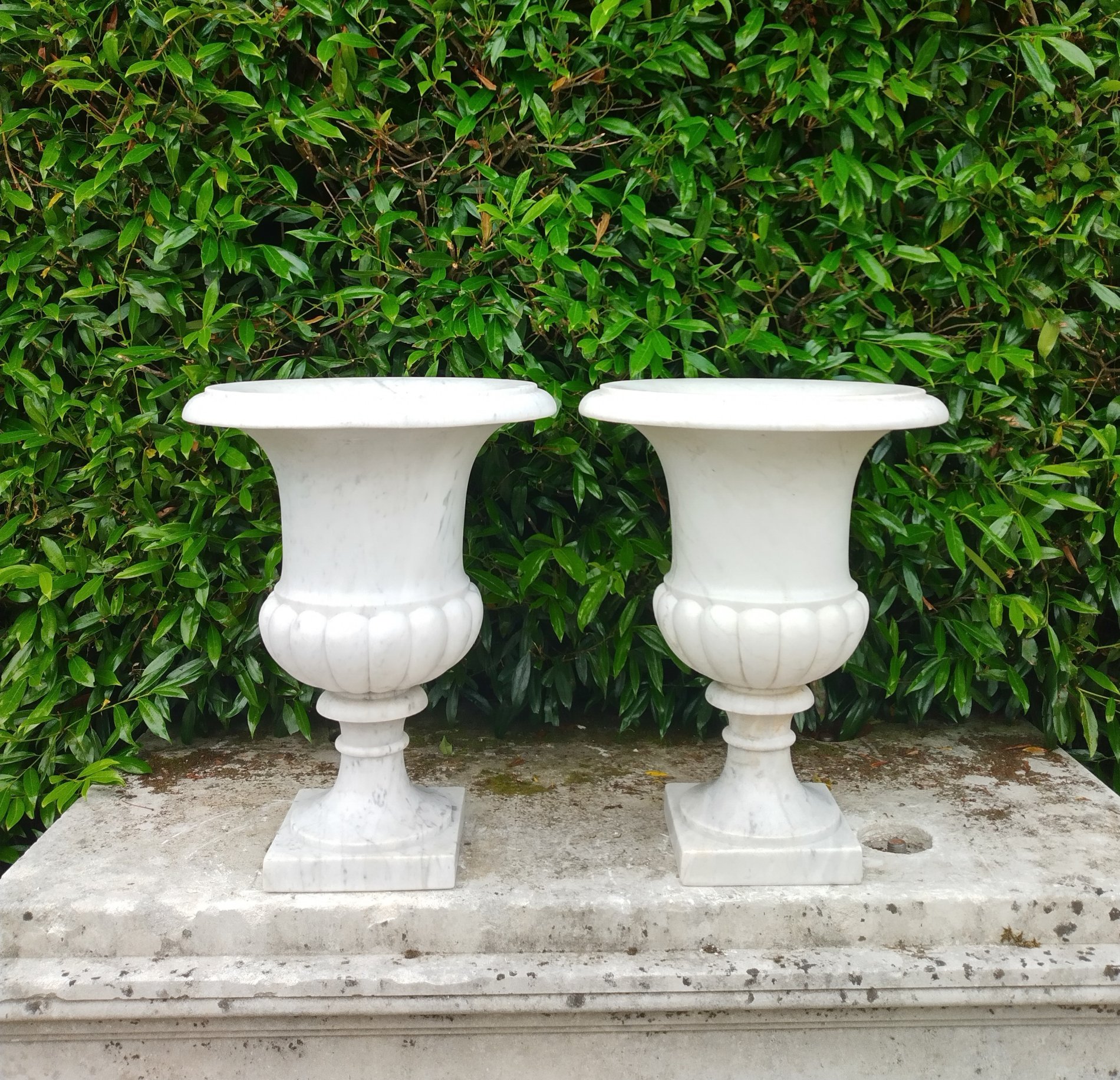 A similar pair of carved white marble urns