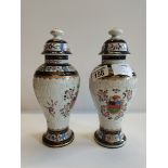 A pair of Porcelain vases in Chinese Export style. Lid on one of the vases has a couple of chips