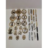 A collection of horse brasses and pocket penknifes