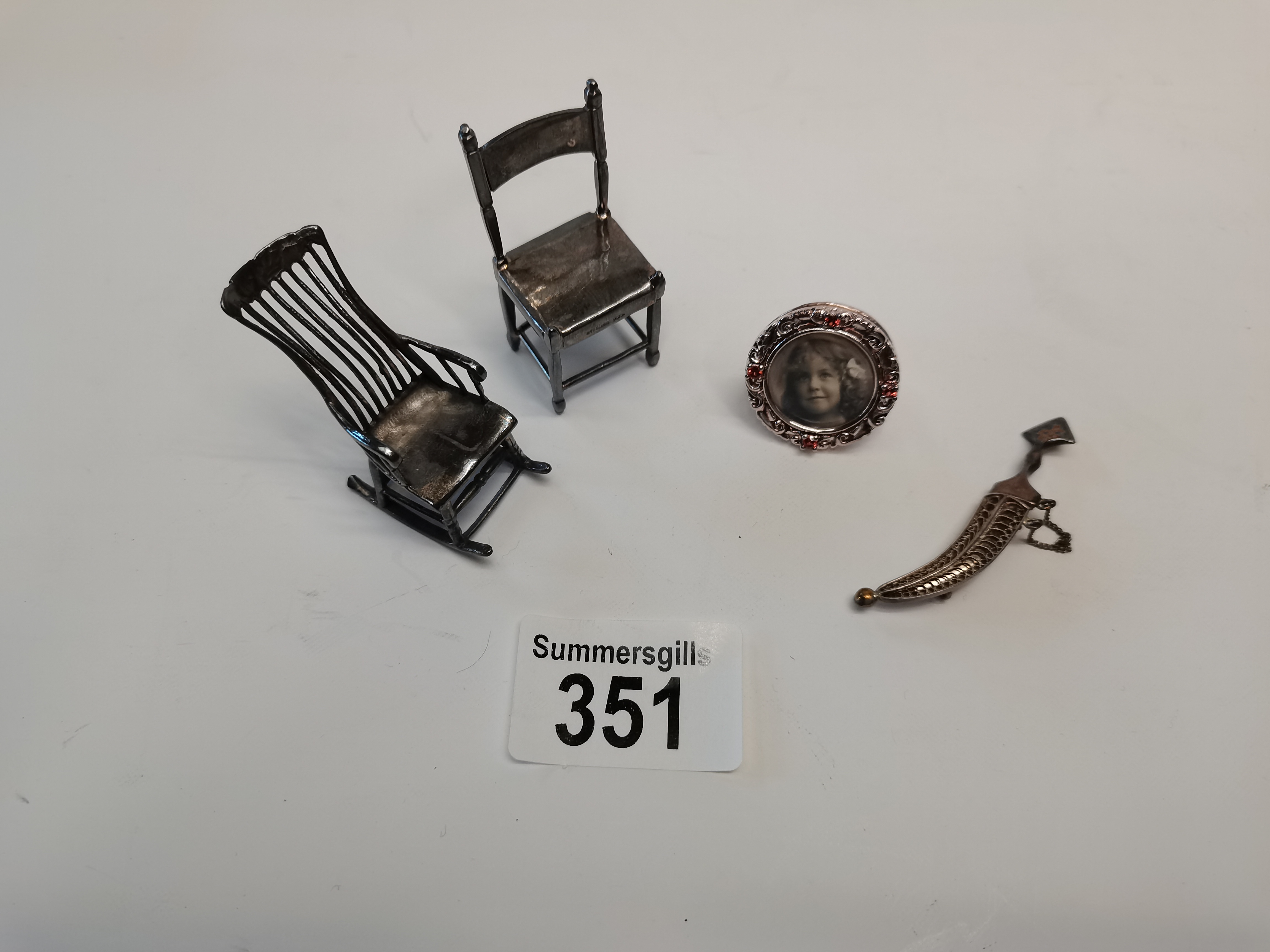 x2 Silver miniature chairs, miniature silver picture frame and a miniature silver dagger brooch.