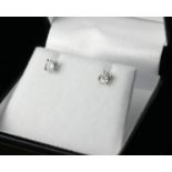 A PAIR OF 18CT WHITE GOLD AND ROUND BRILLIANT CUT SOLITAIRE DIAMOND STUDS Four claw setting.