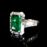 AN 18CT WHITE GOLD, EMERALD AND DIAMOND RING. The emerald surrounded by baguette cut diamonds and